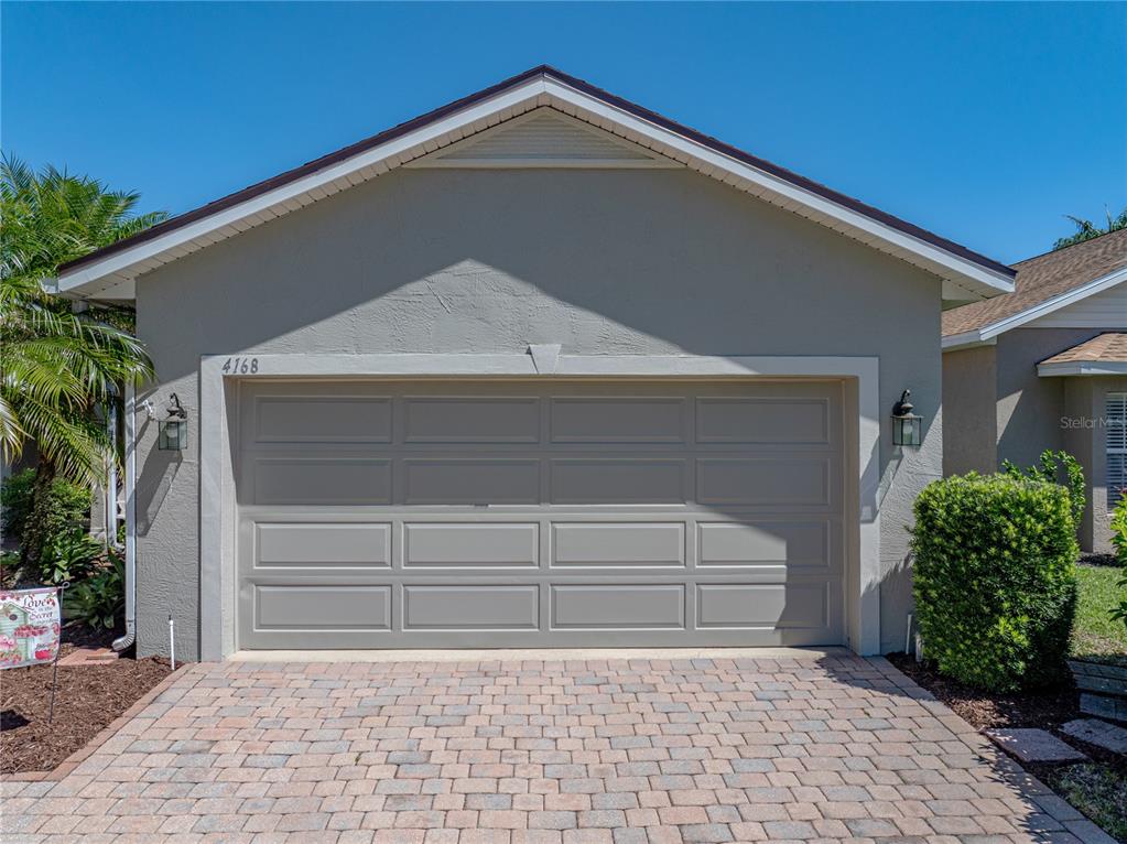 A single-story house exterior features a beige garage door and a paved driveway — 4168 ABERDEEN LANE, LAKE WALES, FL