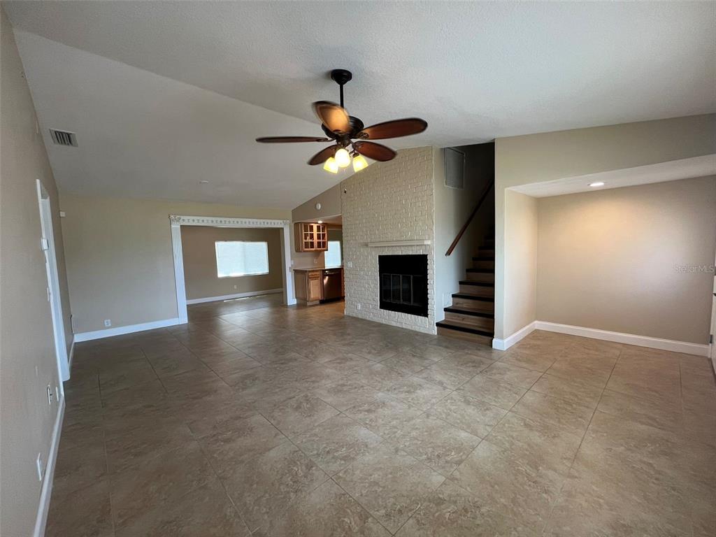 A living room features tile flooring, a brick fireplace, and a staircase leading upstairs — 671 SPRING LAKE BOULEVARD NW, PORT CHARLOTTE, FL