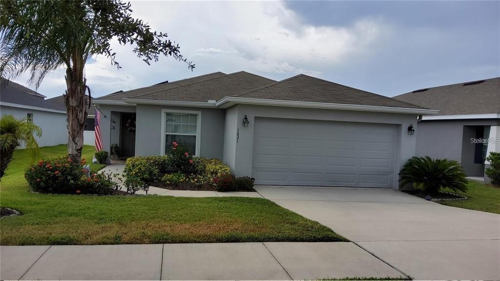 A single-story house with a gray exterior, a two-car garage, and a landscaped front yard — 1531 WOODLARK DRIVE, HAINES CITY, FL