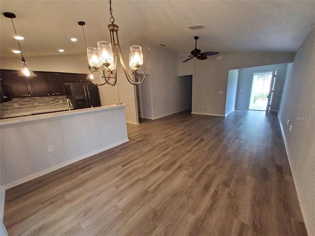 An open-concept living area features wood-look flooring, a kitchen island, and a ceiling fan — 1531 WOODLARK DRIVE, HAINES CITY, FL