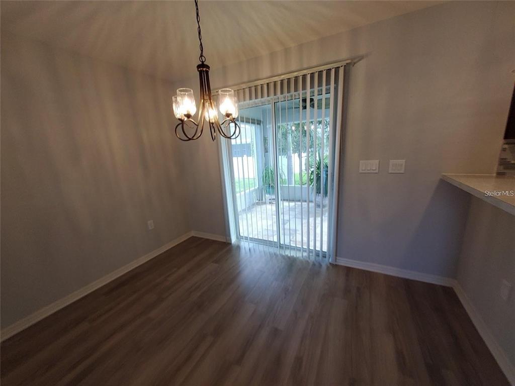 A dining area features wood-look flooring, a hanging chandelier, and sliding glass doors to a patio — 1531 WOODLARK DRIVE, HAINES CITY, FL