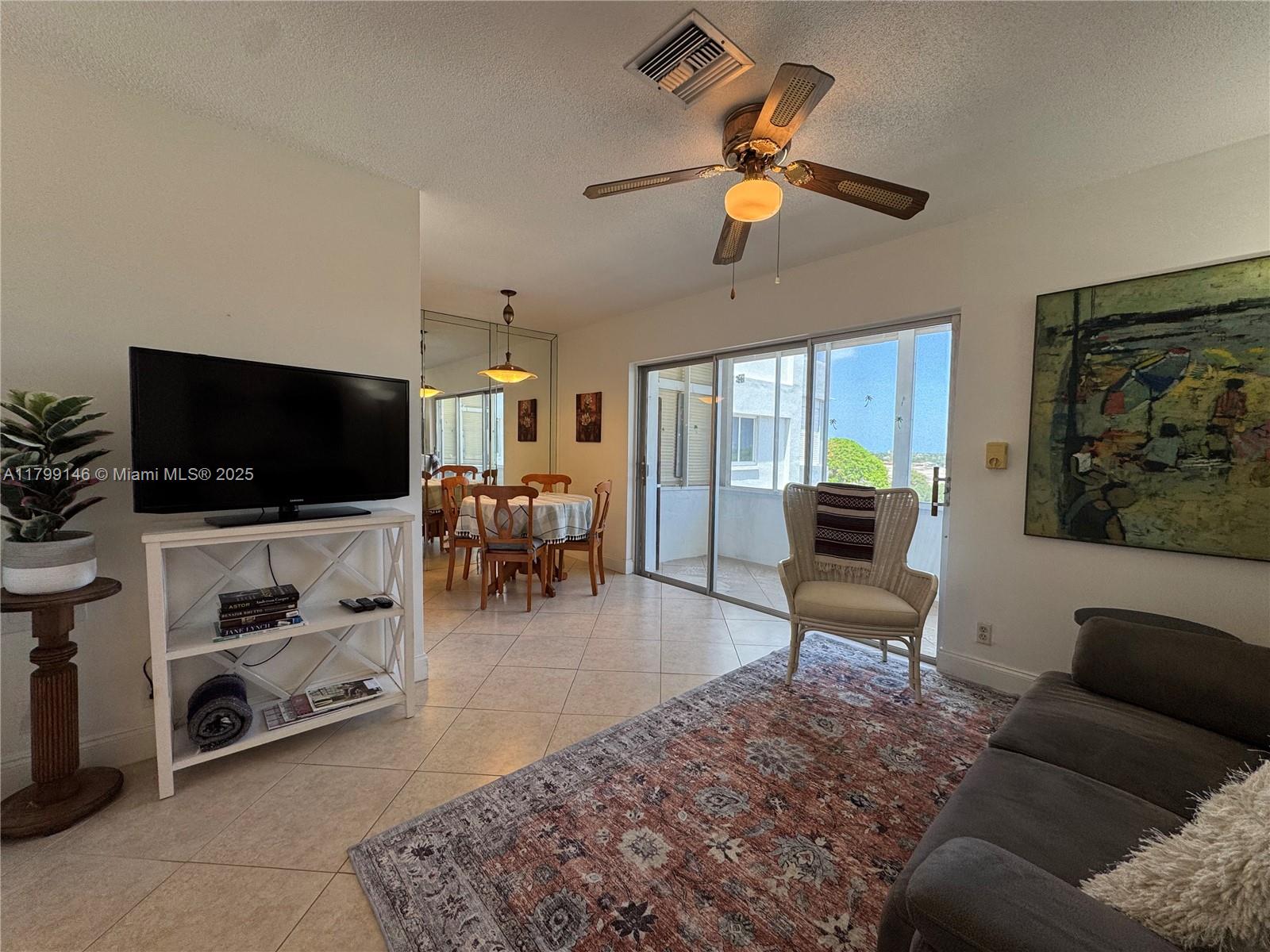 A living room with tile floors, a ceiling fan, a television, and a dining area — 1700 Pierce St # 702, Hollywood FL 33020, HOLLYWOOD, FL