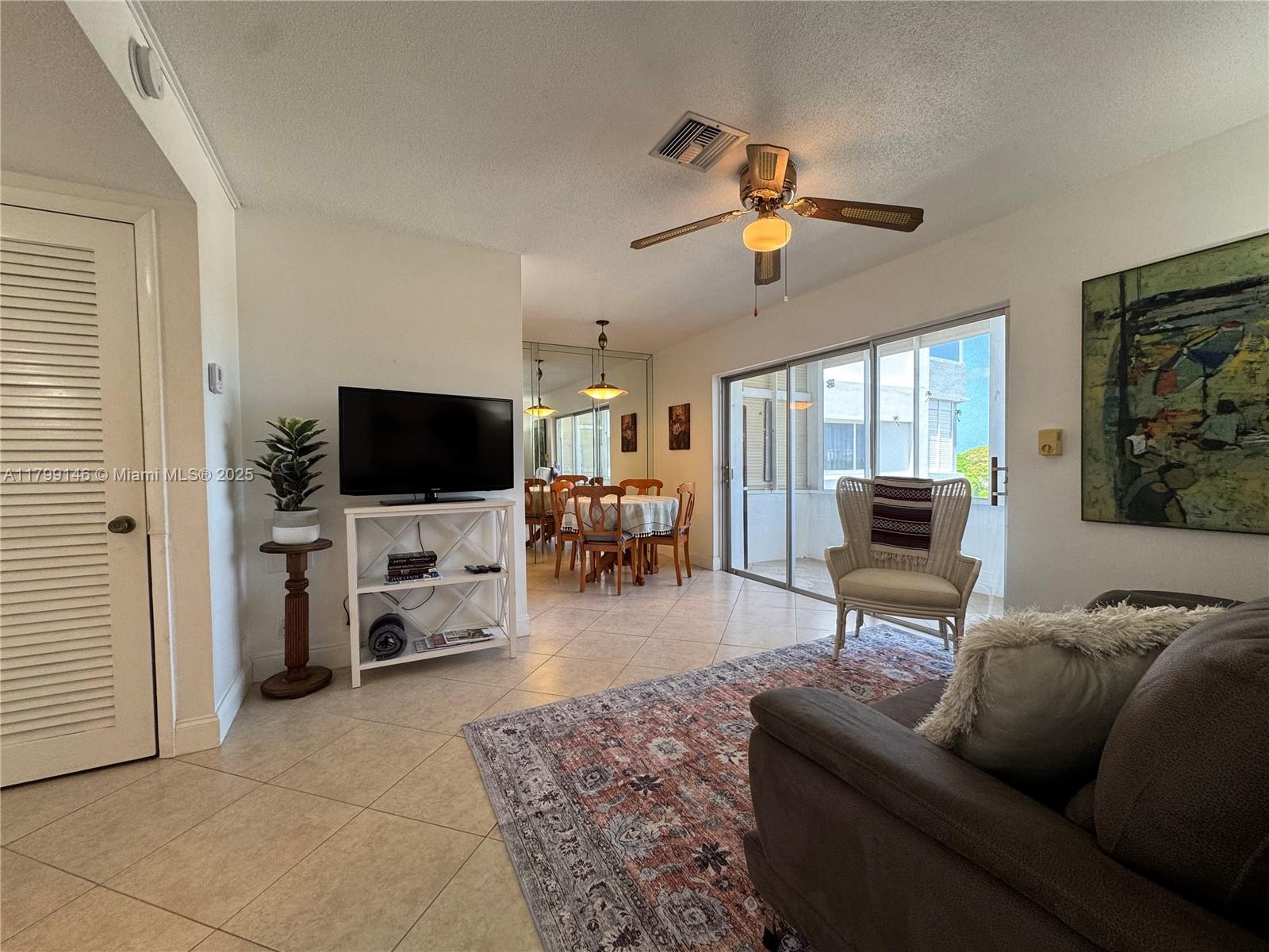 A living room with tile floors, a ceiling fan, a television, and a dining area — 1700 Pierce St # 702, Hollywood FL 33020, HOLLYWOOD, FL