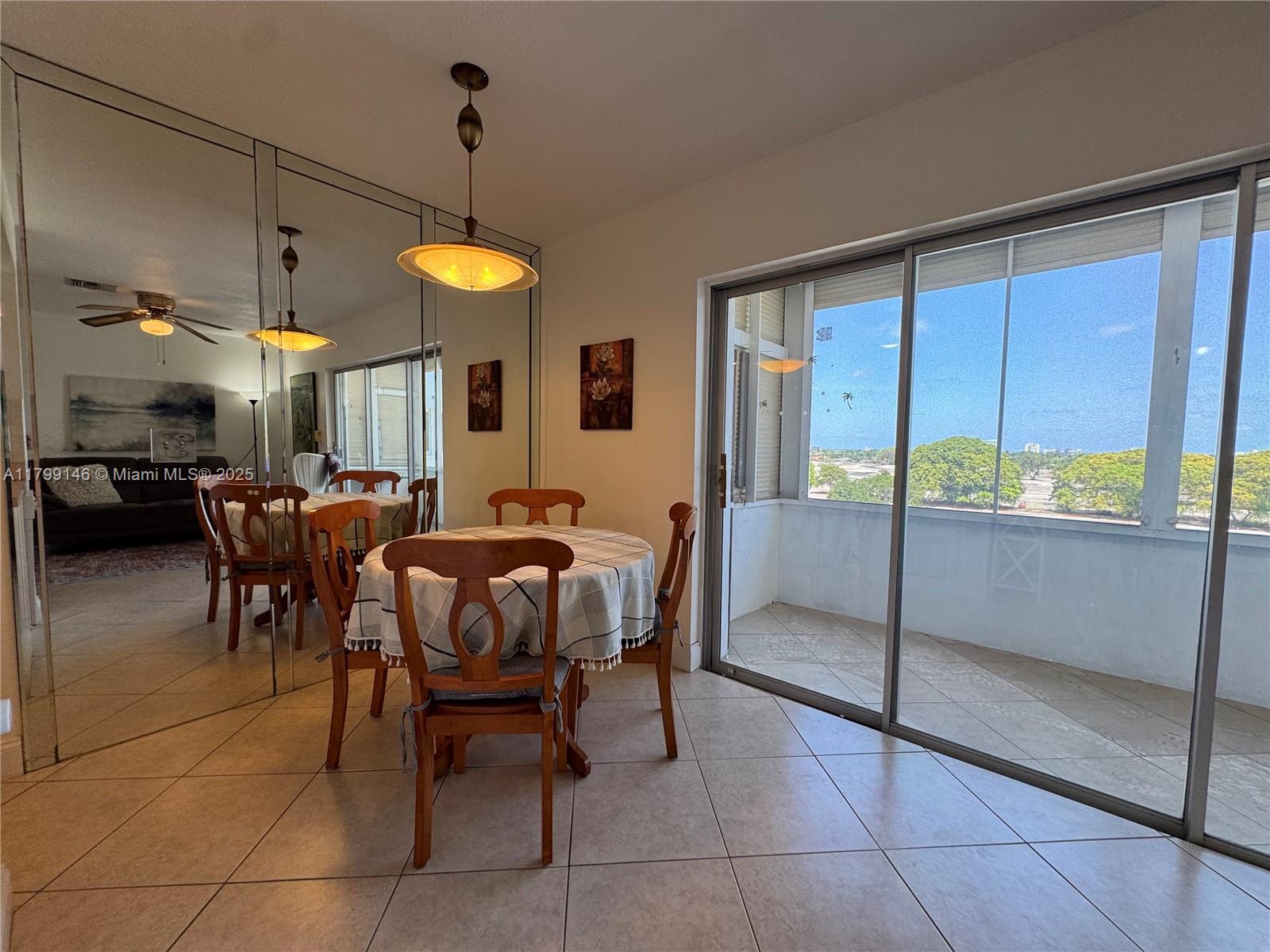 A dining area features a round table, mirrored walls, tile flooring, and a sliding glass door — 1700 Pierce St # 702, Hollywood FL 33020, HOLLYWOOD, FL