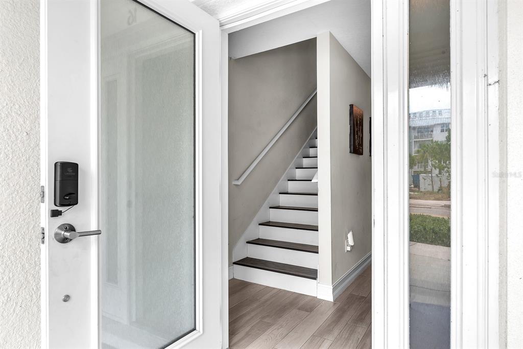 An open front door reveals a staircase with dark treads and white risers inside — 5351 BRIDGE STREET UNIT 16, TAMPA, FL
