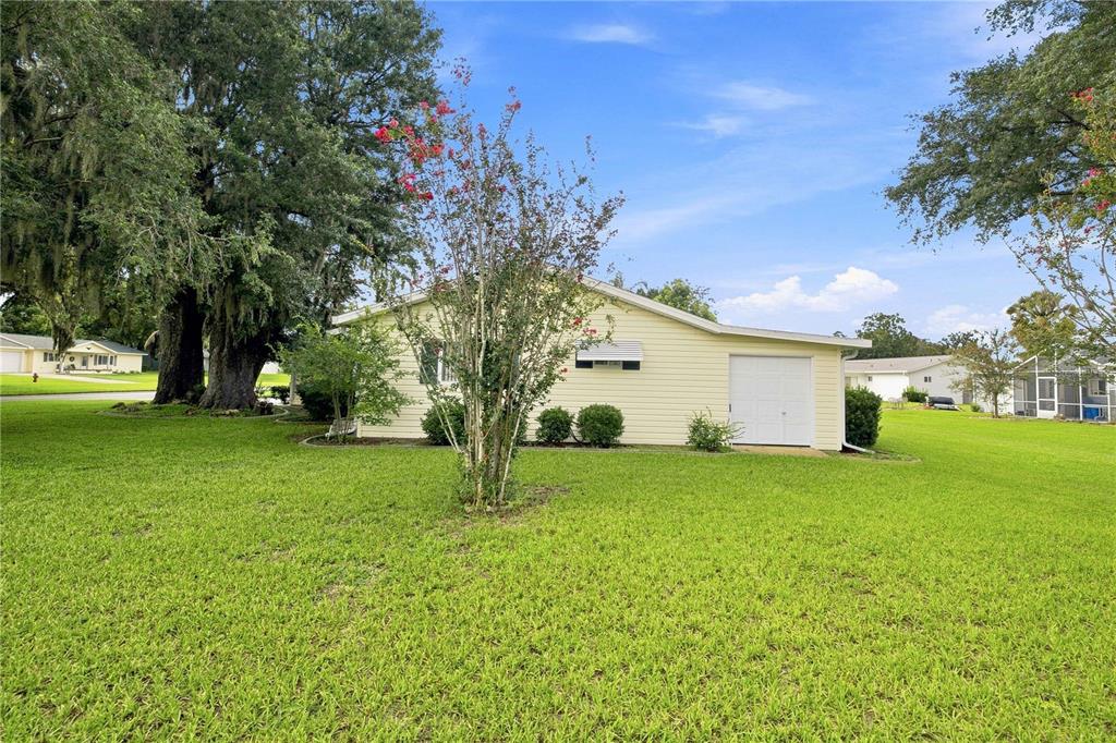 A light yellow house with a single-car garage sits on a large, grassy lawn — 10298 SE 176TH STREET, SUMMERFIELD, FL