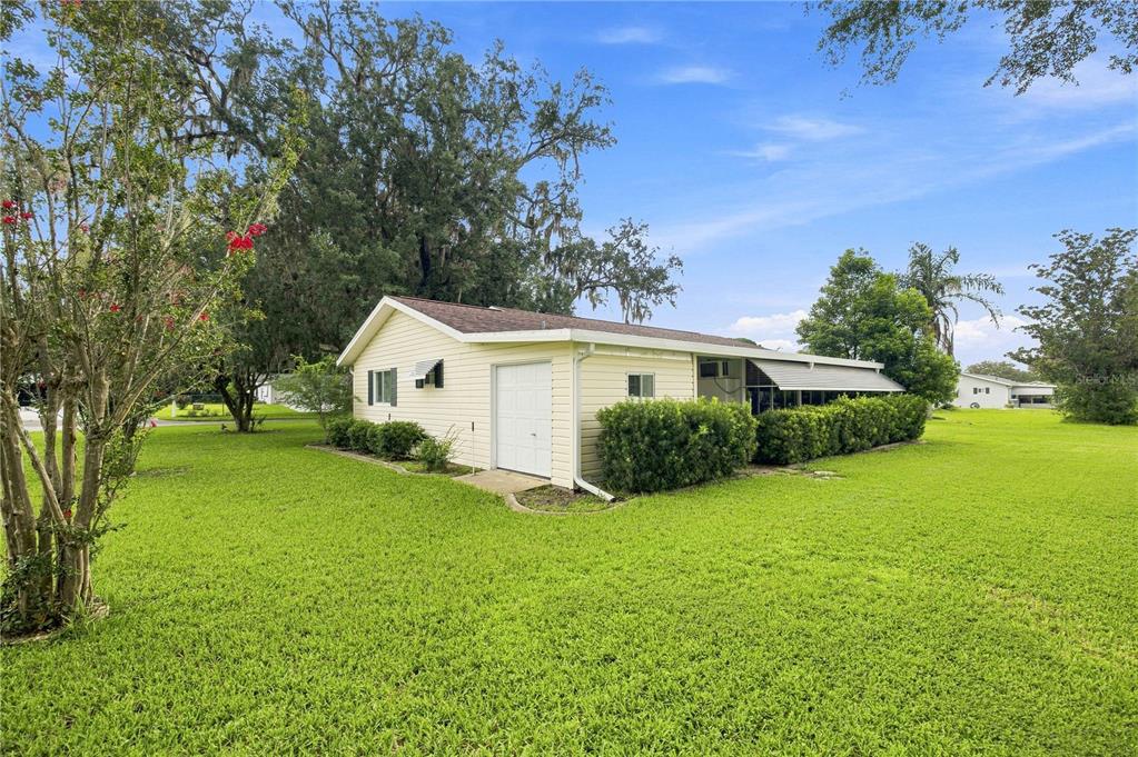 A light-colored house with a garage and a screened-in porch sits on a grassy lawn — 10298 SE 176TH STREET, SUMMERFIELD, FL