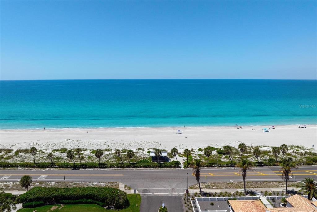 An elevated view of a sandy beach, turquoise ocean, and a coastal road with palm trees — 581 ROUNTREE DRIVE, LONGBOAT KEY, FL