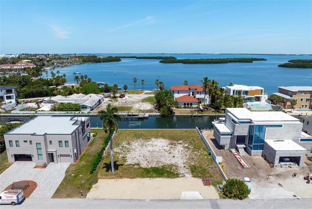 An aerial view shows a vacant waterfront lot situated between two modern residential homes — 581 ROUNTREE DRIVE, LONGBOAT KEY, FL