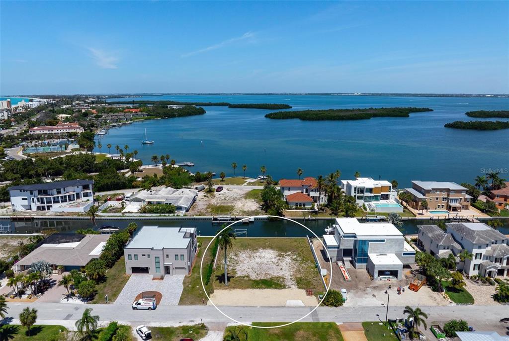 An aerial view shows a vacant waterfront lot situated between two modern houses — 581 ROUNTREE DRIVE, LONGBOAT KEY, FL