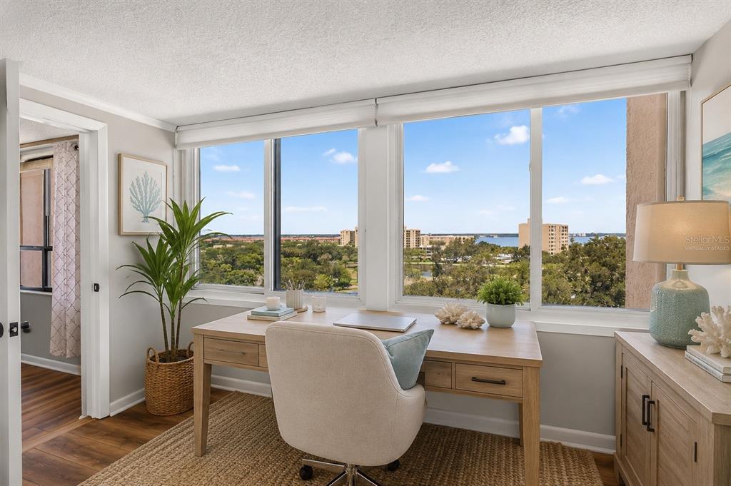 A home office with a wooden desk, an upholstered chair, and a view of the water — 2621 COVE CAY DRIVE UNIT 802, CLEARWATER, FL