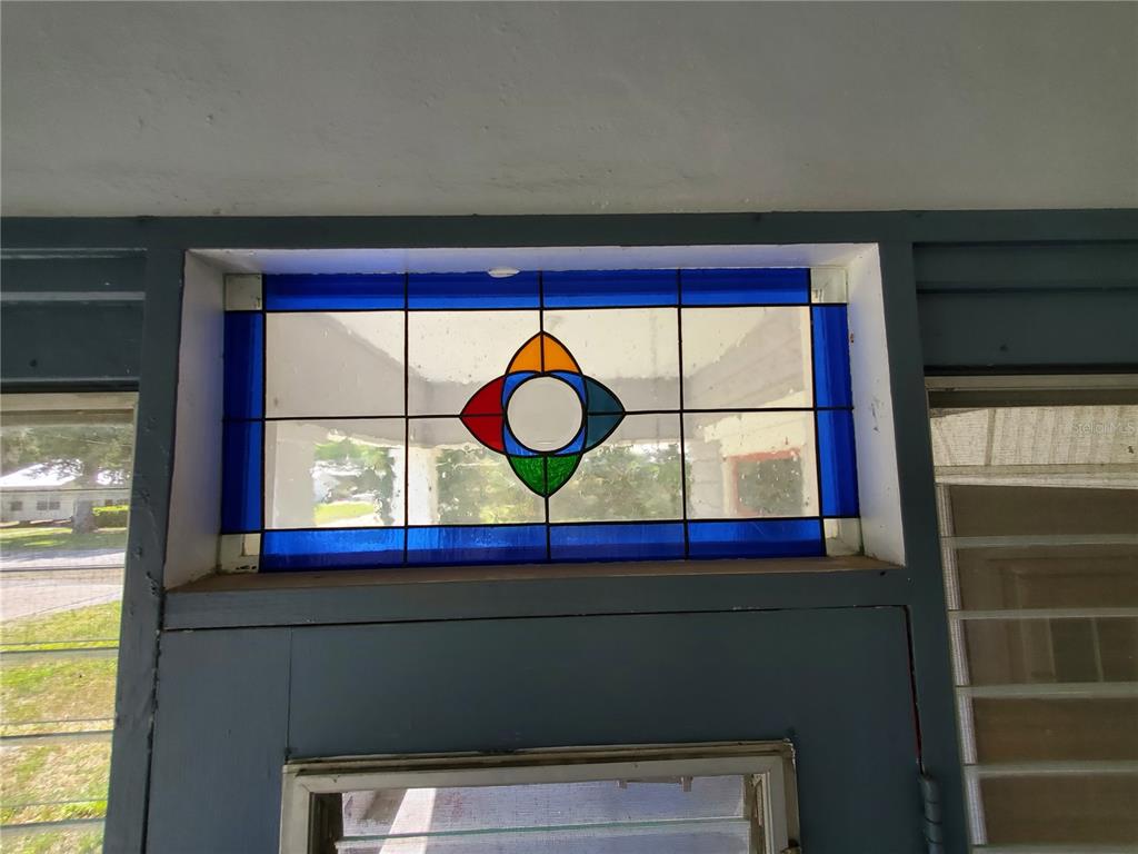 A rectangular stained glass transom window with a central four-petal design sits above a door — 23882 NW 187TH AVENUE, HIGH SPRINGS, FL