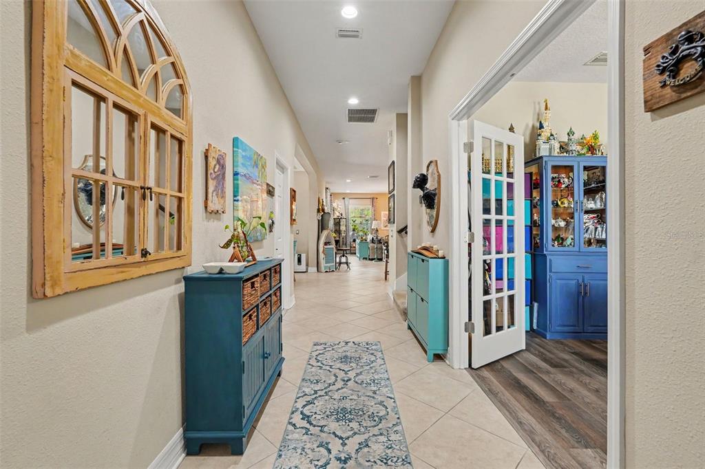 A hallway with tile flooring, a blue cabinet, a runner rug, and a glass-paned door — 7110 REDROOT COURT, WESLEY CHAPEL, FL
