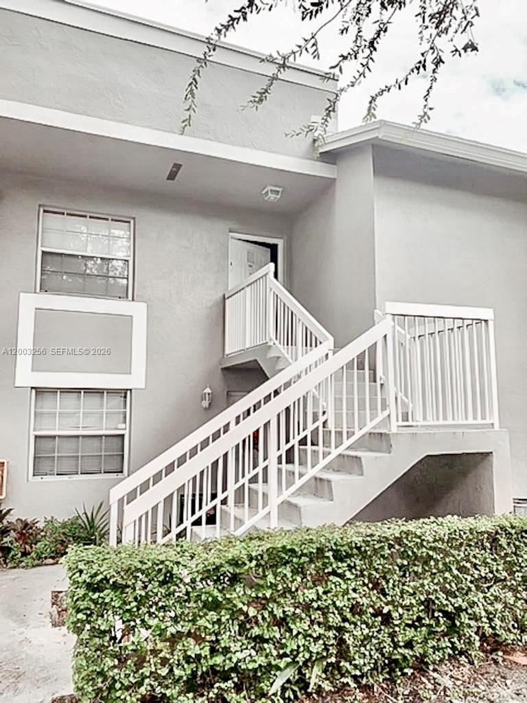 An exterior view of a two-story building featuring white stairs leading to an upper entrance — 464 NE 210th Cir Ter # 10A, Miami FL 33179, MIAMI, FL