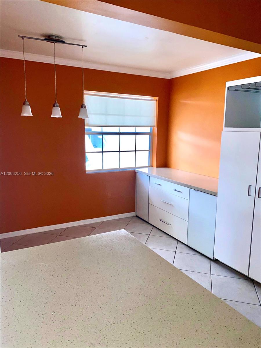 A kitchen features orange walls, white cabinets, a window, and three pendant lights — 464 NE 210th Cir Ter # 10A, Miami FL 33179, MIAMI, FL