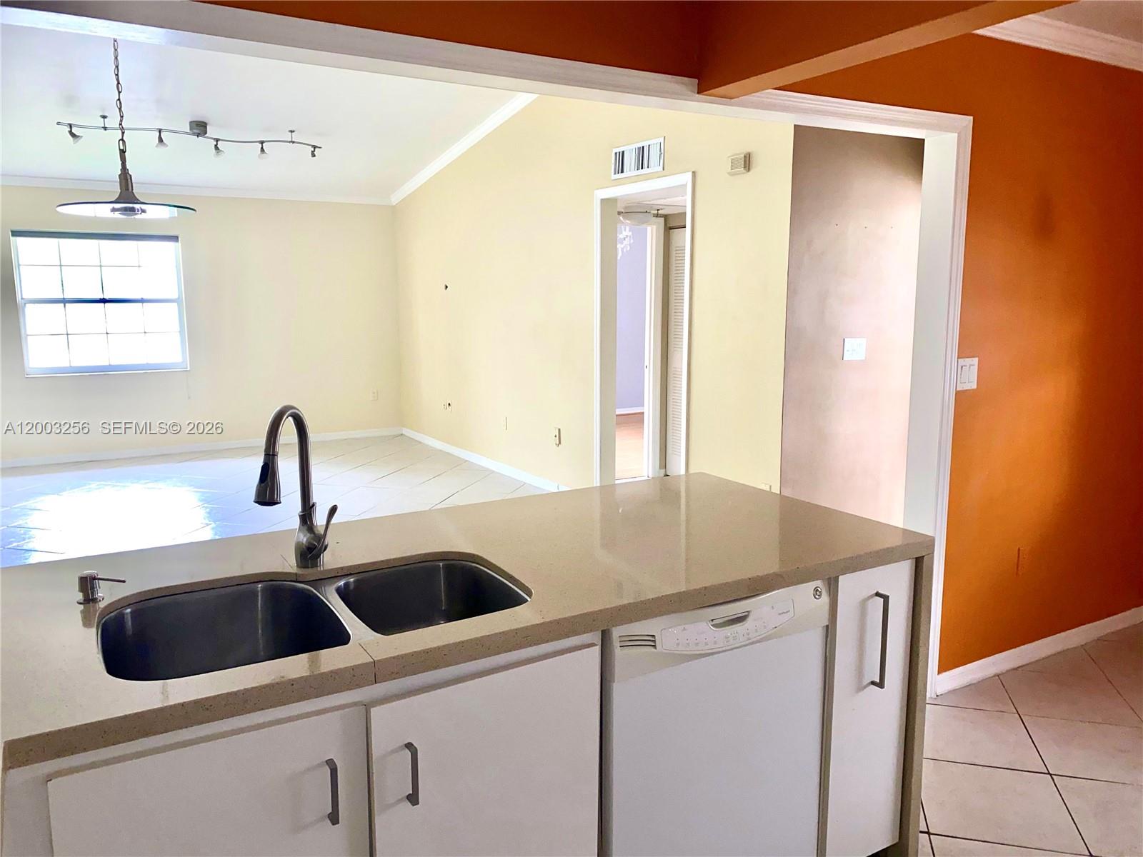 A kitchen island with a double sink and dishwasher overlooks an adjacent living area — 464 NE 210th Cir Ter # 10A, Miami FL 33179, MIAMI, FL