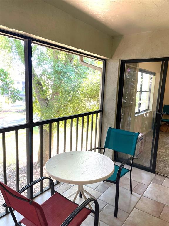 A screened-in balcony features a small round table, two chairs, and tile flooring — 4601 46TH STREET COURT W UNIT 202B, BRADENTON, FL