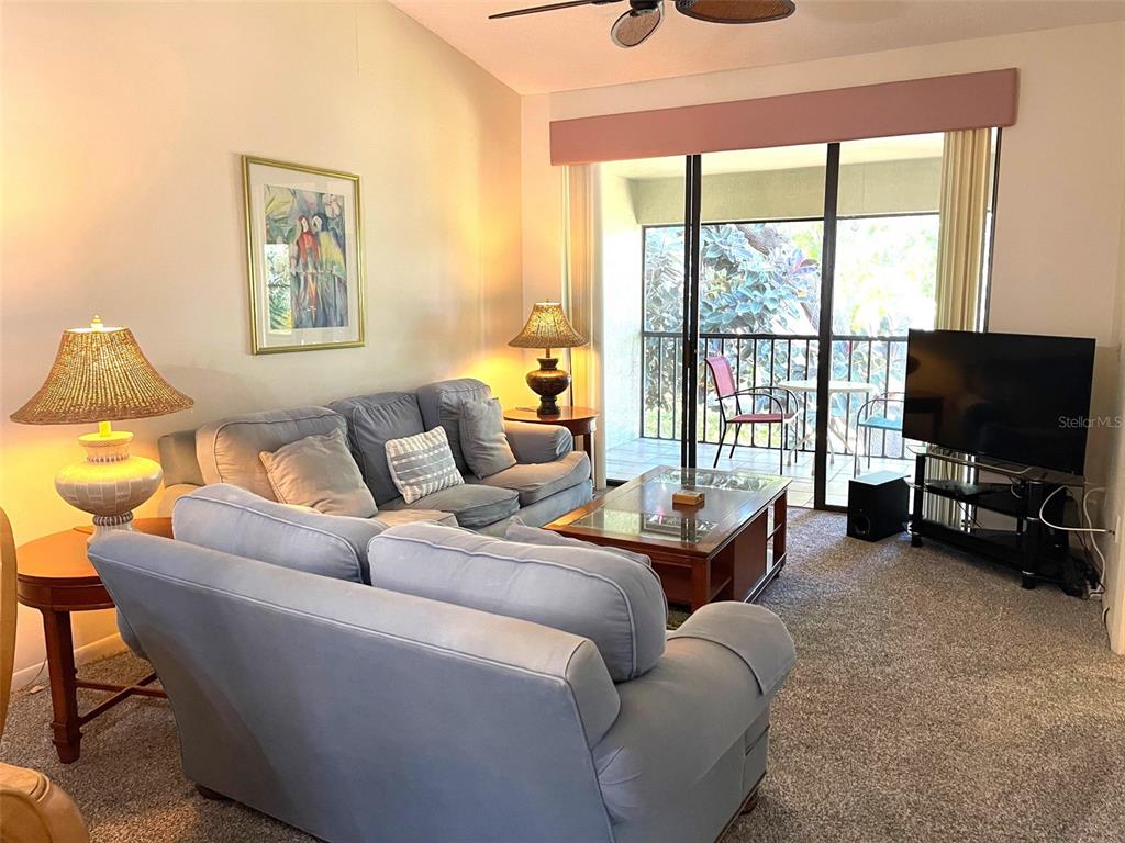A living room features a light blue sofa, a coffee table, and a sliding glass door — 4601 46TH STREET COURT W UNIT 202B, BRADENTON, FL