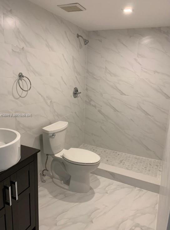 A bathroom features a white toilet, a dark vanity, and a walk-in shower with marble-look tiles — 6175 NW 186th St # 305, Hialeah FL 33015, HIALEAH, FL