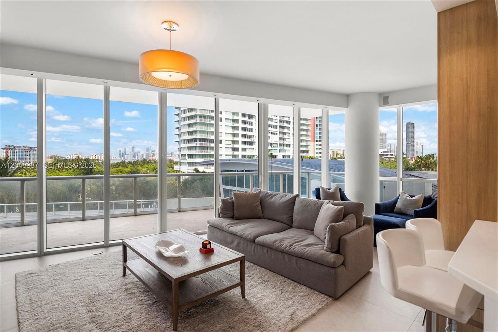 A living room features a gray sofa, coffee table, and floor-to-ceiling windows with city views — 100 S Pointe Dr # 501, Miami Beach FL 33139, MIAMI BEACH, FL