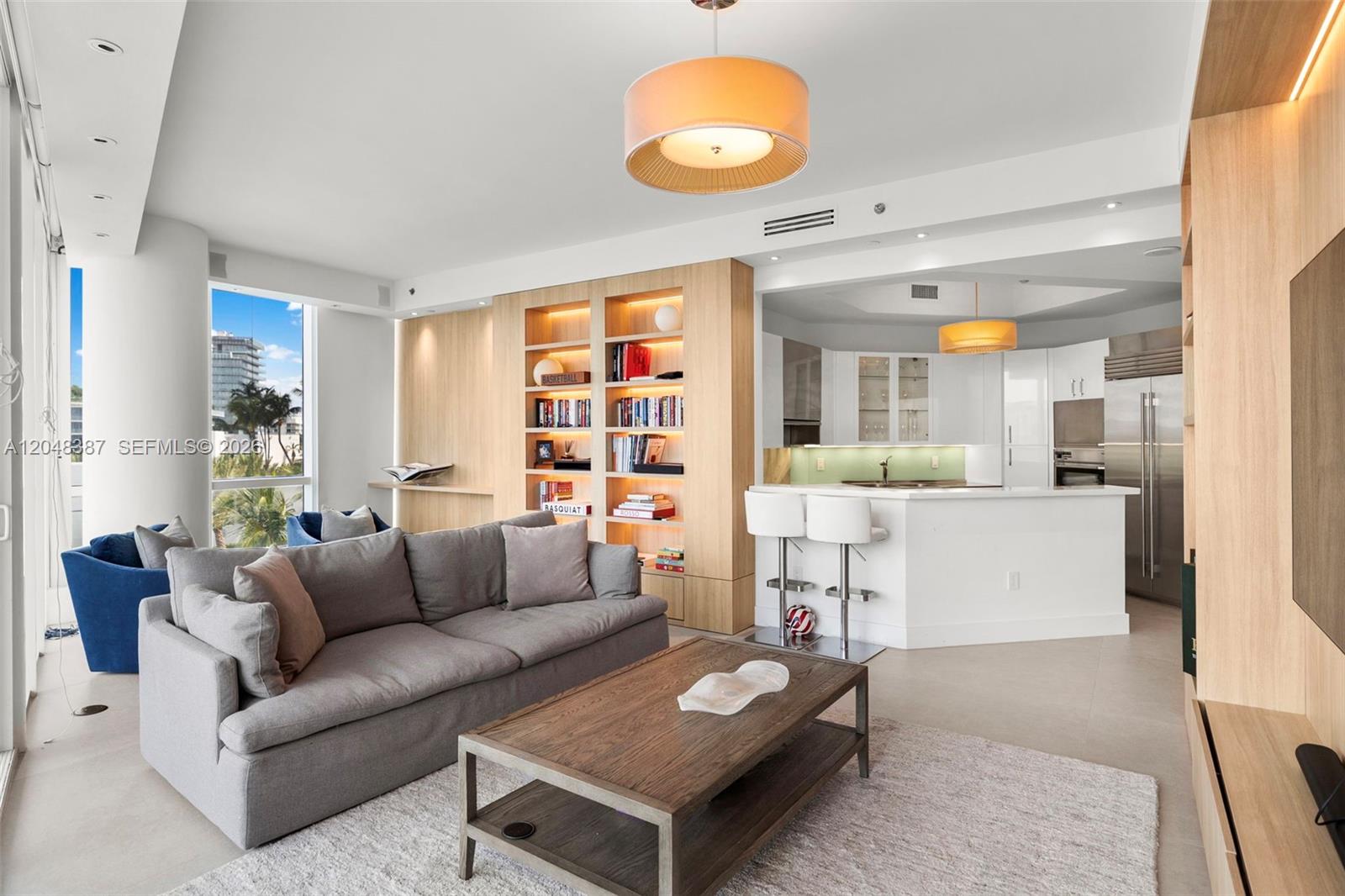 A modern living room with a grey sofa, wooden coffee table, and open-concept kitchen — 100 S Pointe Dr # 501, Miami Beach FL 33139, MIAMI BEACH, FL