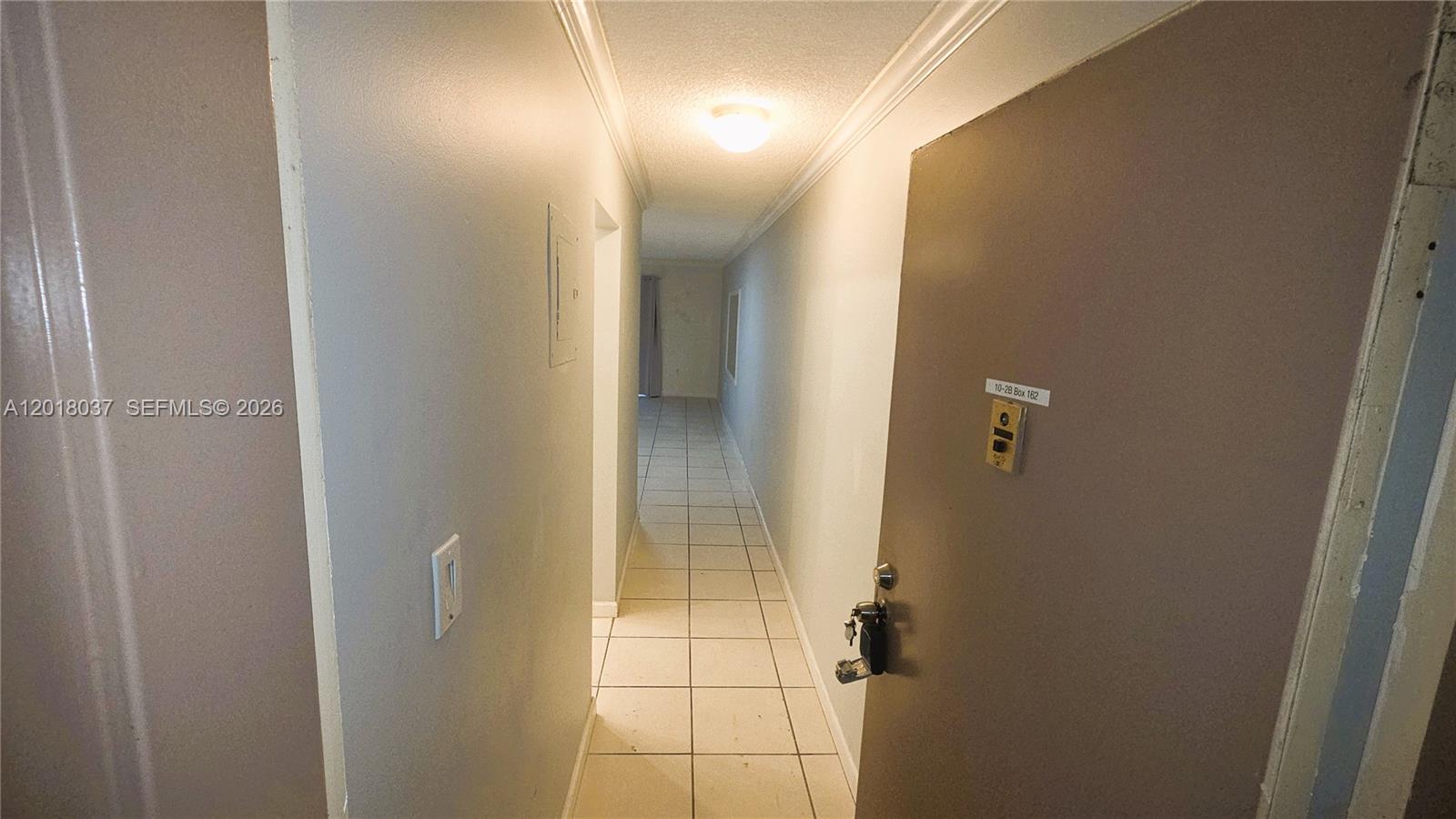 A hallway with white tile flooring leads from an open door toward a window — 4344 NW 9th Ave # 2B, Deerfield Beach FL 33064, DEERFIELD BEACH, FL