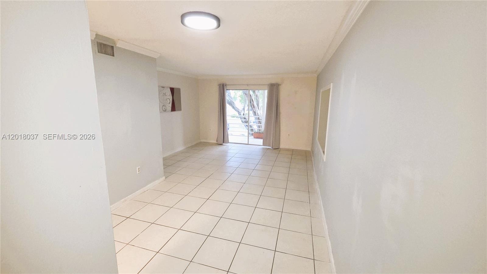 A living room features light-colored tile flooring, white walls, and a sliding glass door — 4344 NW 9th Ave # 2B, Deerfield Beach FL 33064, DEERFIELD BEACH, FL