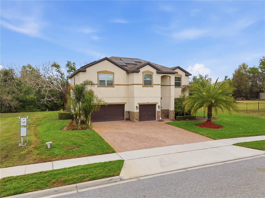 A two-story house with a tan stucco exterior, stone accents, and a brick paver driveway — 3129 PINENUT DRIVE, APOPKA, FL