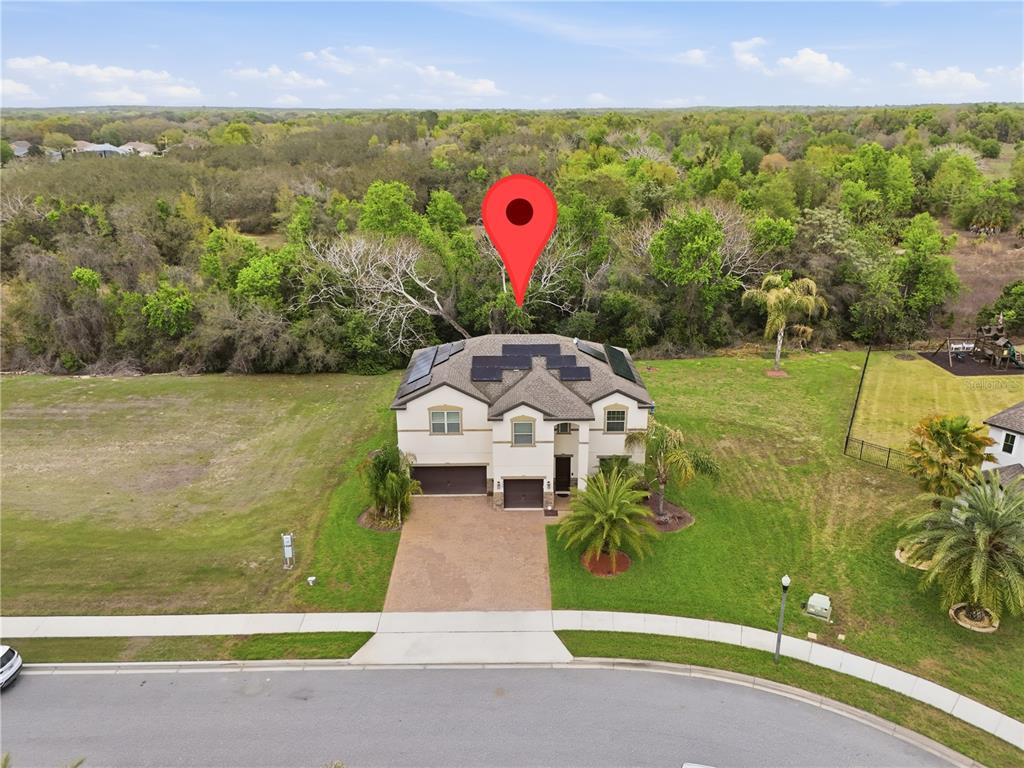 An aerial view shows a two-story house with solar panels on the roof and a driveway — 3129 PINENUT DRIVE, APOPKA, FL