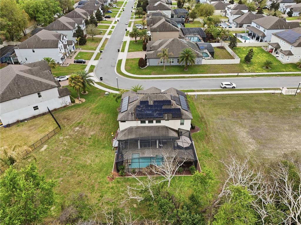 An aerial view shows a two-story house with solar panels and a screened-in pool — 3129 PINENUT DRIVE, APOPKA, FL