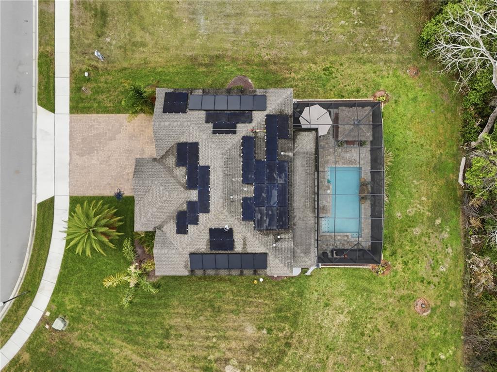 An aerial view shows a house with solar panels on the roof and a screened pool — 3129 PINENUT DRIVE, APOPKA, FL
