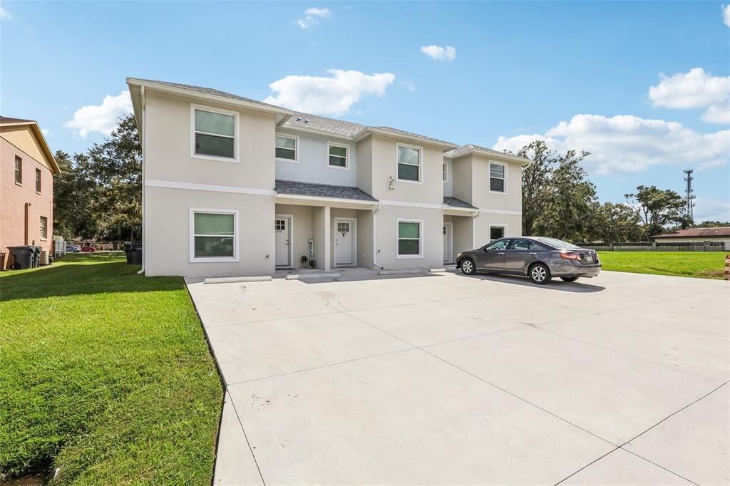 A two-story multi-family building with a concrete driveway and a parked gray sedan — 1108 FOX LAKE DRIVE, LAKELAND, FL