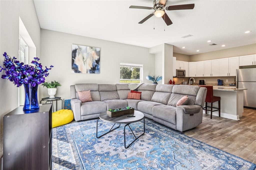A living room with a gray sectional sofa, blue area rug, and an open kitchen — 1108 FOX LAKE DRIVE, LAKELAND, FL