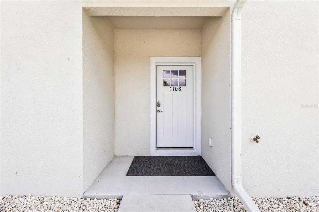A white front door with a small window and house number 1108 sits in a recessed entryway — 1108 FOX LAKE DRIVE, LAKELAND, FL