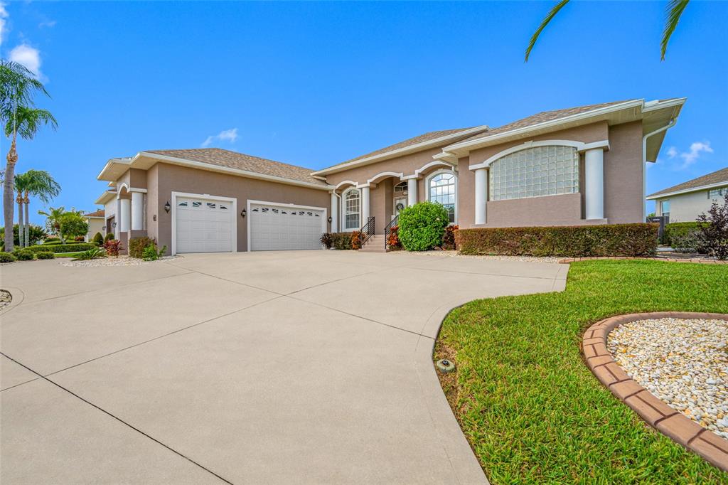 A single-story house with a beige stucco exterior, a three-car garage, and a concrete driveway — 6750 HUNTINGTON HILLS BOULEVARD, LAKELAND, FL