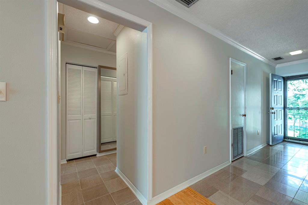 A hallway with tiled floors leads to a closet and an open doorway to outside — 110 N TREMAIN STREET UNIT 202, MOUNT DORA, FL