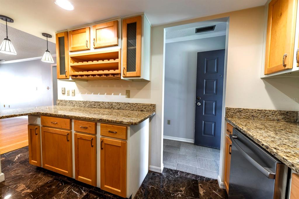 A kitchen features light wood cabinets, granite countertops, and dark marble flooring — 110 N TREMAIN STREET UNIT 202, MOUNT DORA, FL