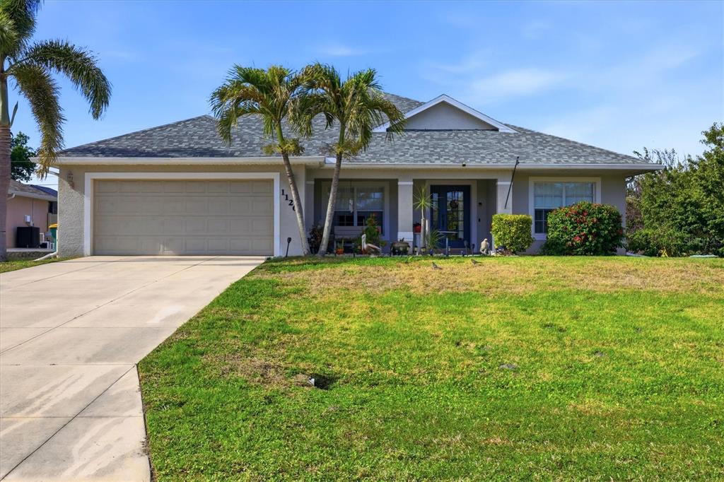 A single-story house with a two-car garage, palm trees, and a concrete driveway — 11200 CARNEGIE AVENUE, ENGLEWOOD, FL
