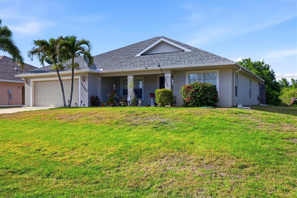 A single-story house with a beige exterior, a gray shingled roof, and a front lawn — 11200 CARNEGIE AVENUE, ENGLEWOOD, FL