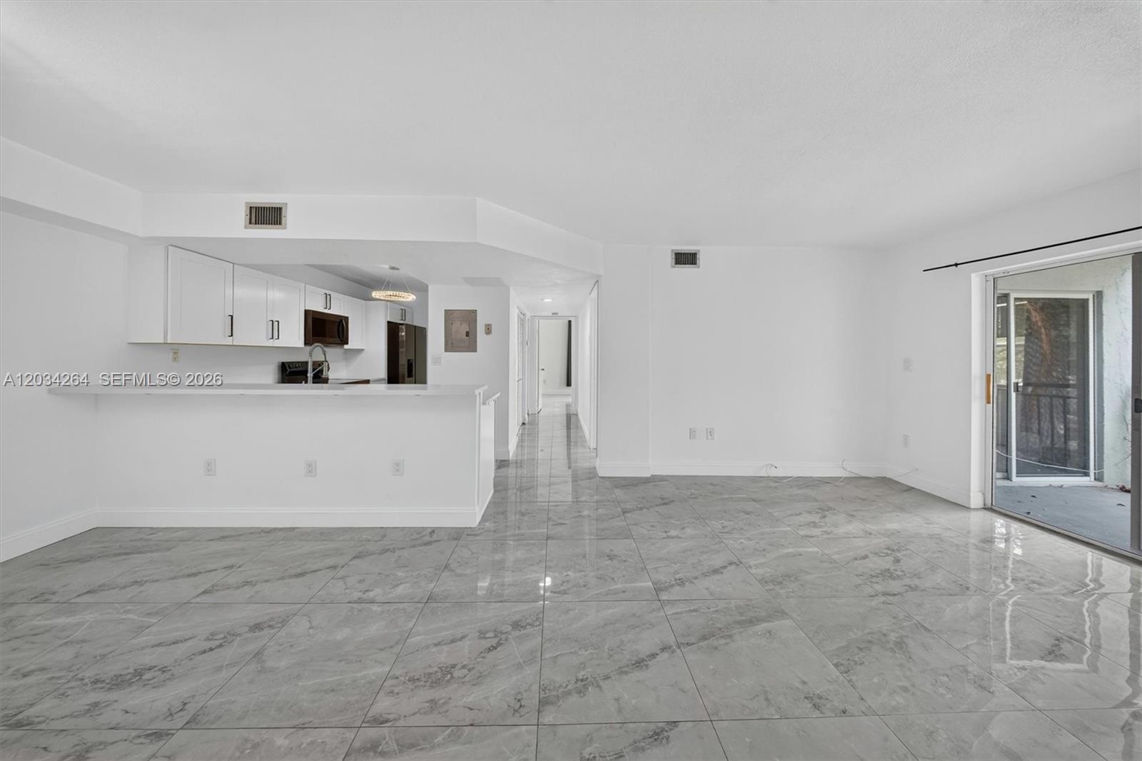 An open-concept living area features white walls, gray marble-look tile flooring, and a kitchen island — 8540 SW 212th St # 202, Cutler Bay FL 33189, CUTLER BAY, FL