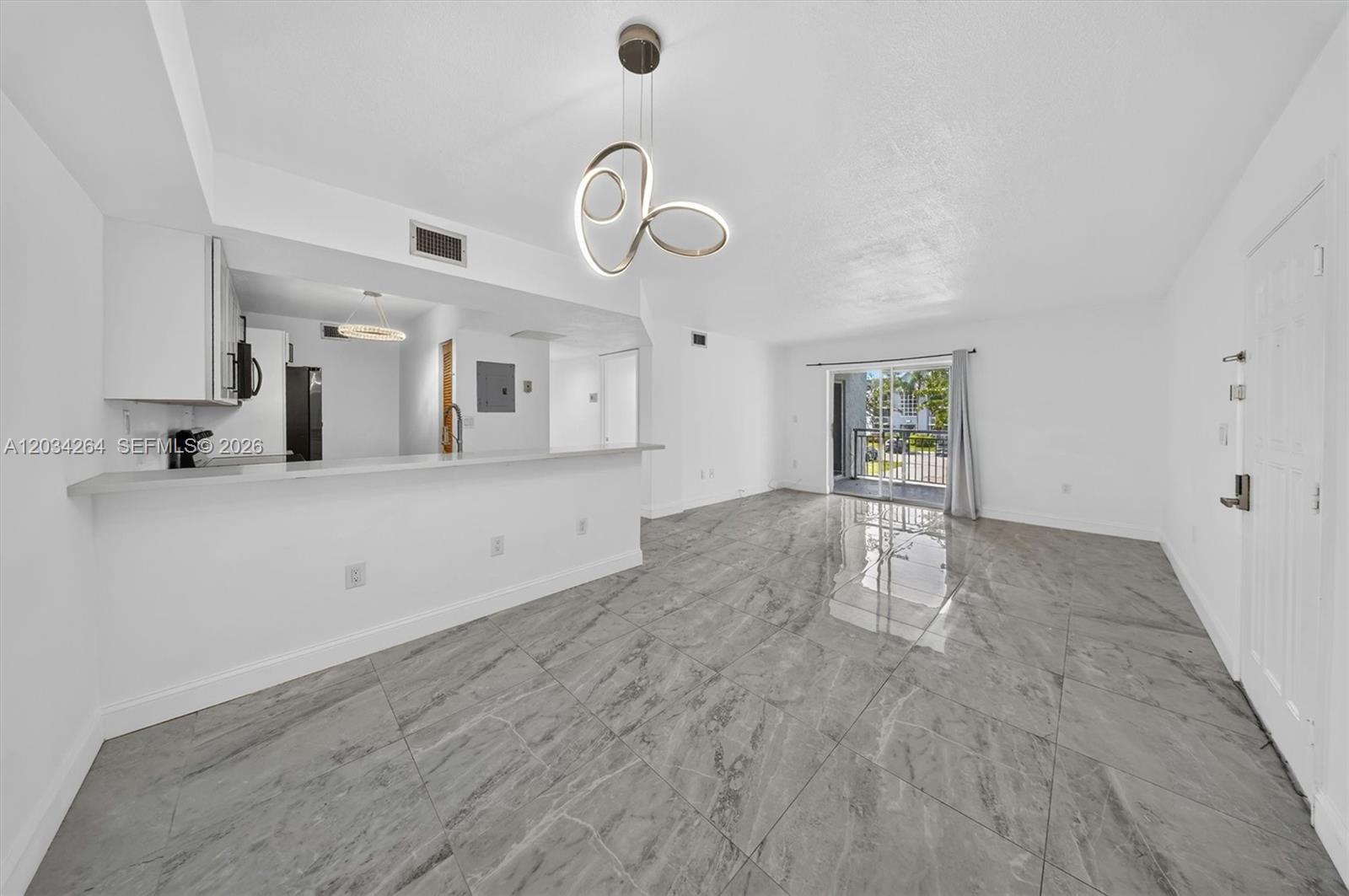 A bright, open-concept living area features gray marble-look tile flooring and a modern pendant light — 8540 SW 212th St # 202, Cutler Bay FL 33189, CUTLER BAY, FL