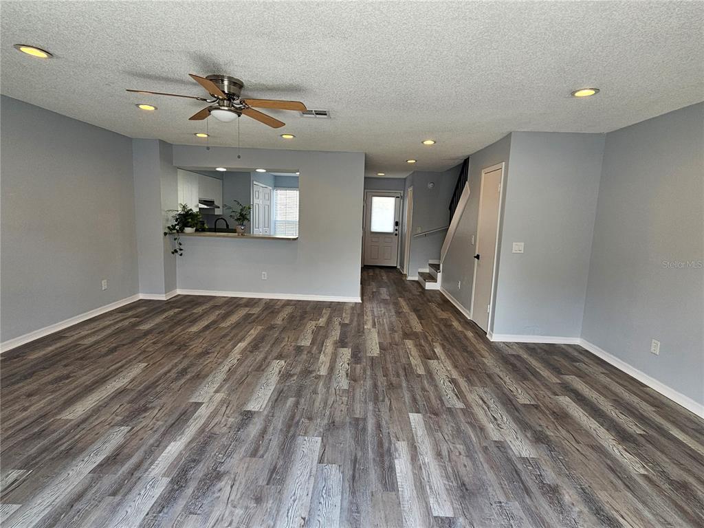 A living room features gray walls, wood-look flooring, recessed lighting, and a kitchen pass-through window — 13817 STONE MILL WAY, TAMPA, FL