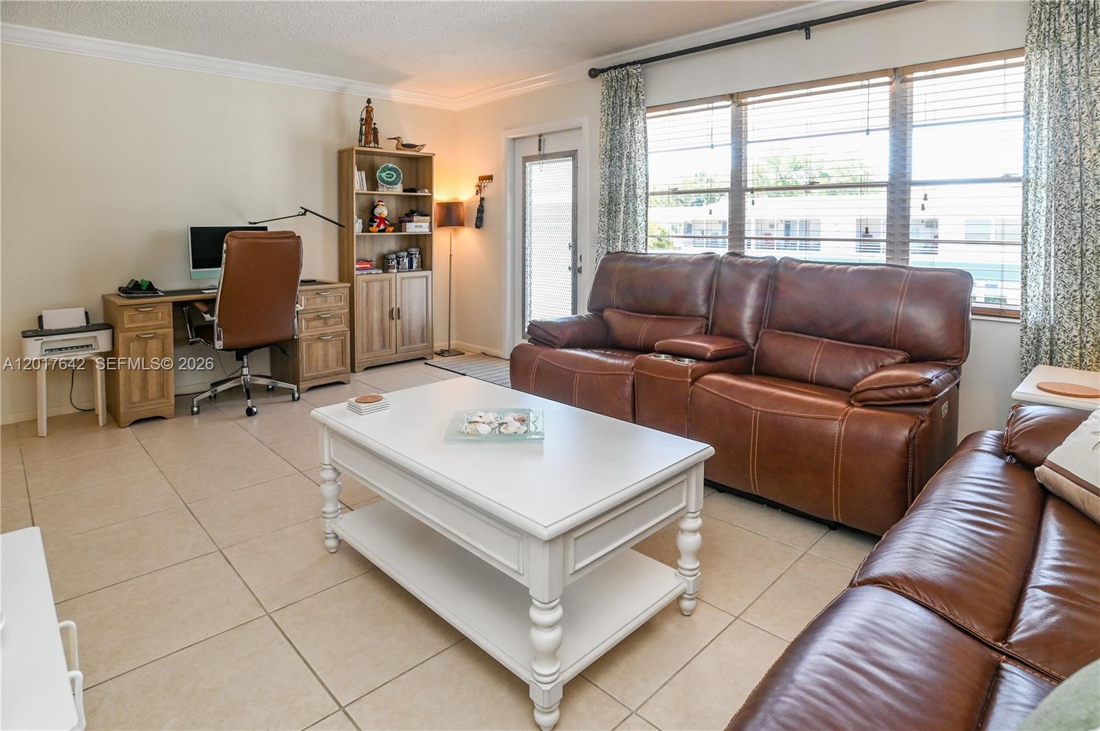 A living room features tile flooring, brown leather sofas, a white coffee table, and a desk — 62 Prescott C # 62, Deerfield Beach FL 33442, DEERFIELD BEACH, FL