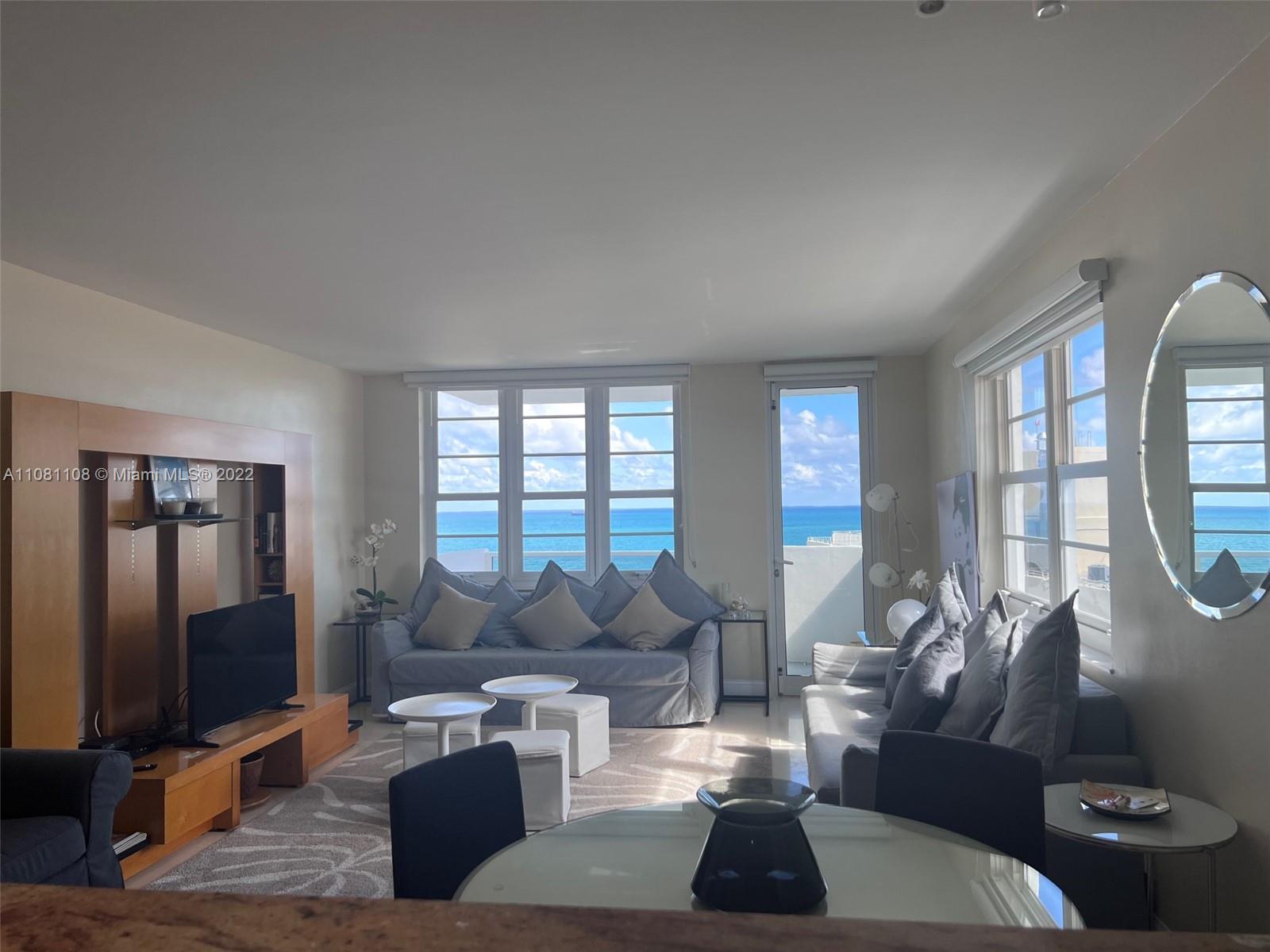 A living room with a sofa, television, and dining area overlooking the ocean — 100 Lincoln Rd # 1121, Miami Beach FL 33139, MIAMI BEACH, FL