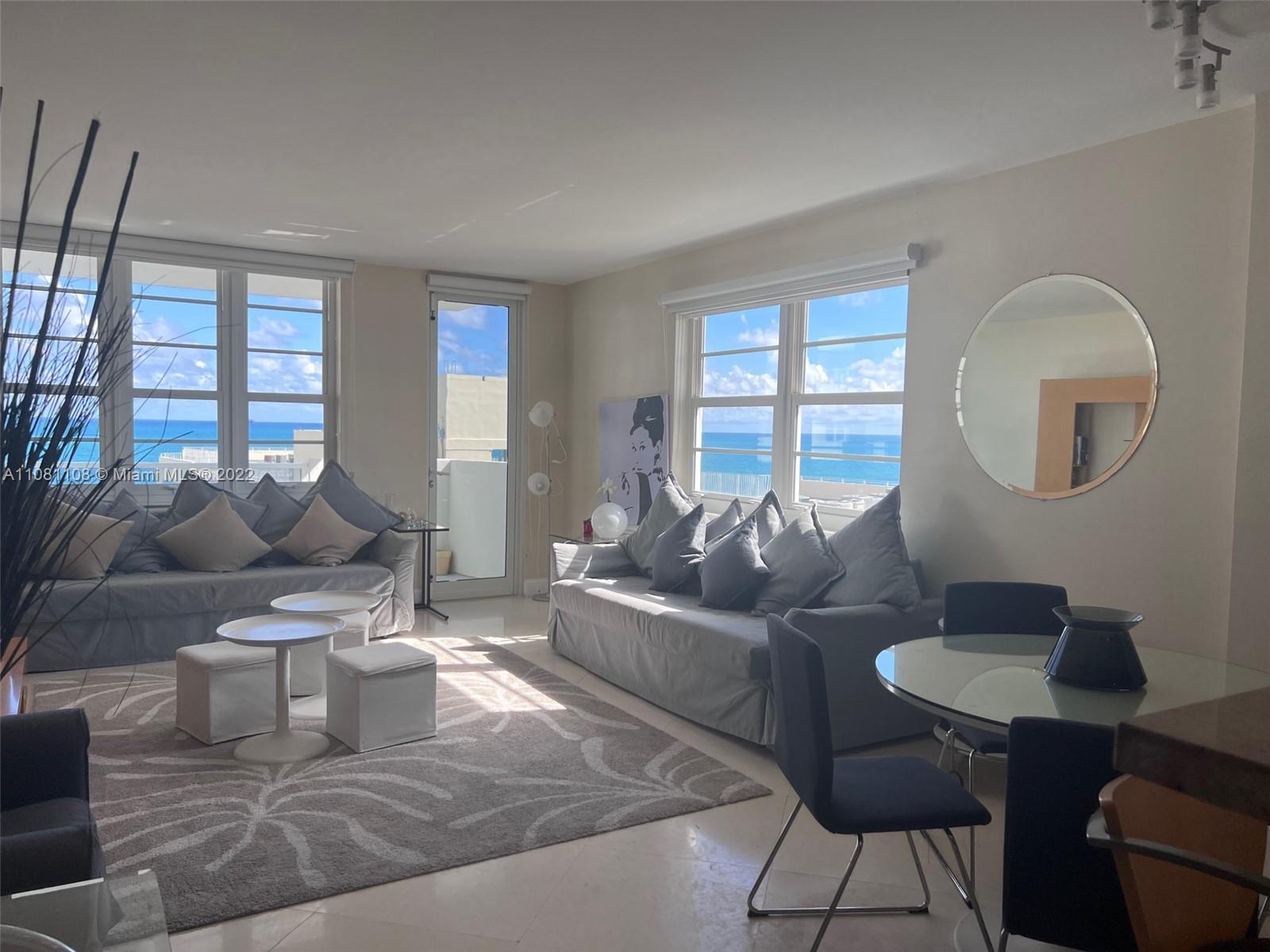A bright living and dining area features two gray sofas, ocean views, and tile flooring — 100 Lincoln Rd # 1121, Miami Beach FL 33139, MIAMI BEACH, FL