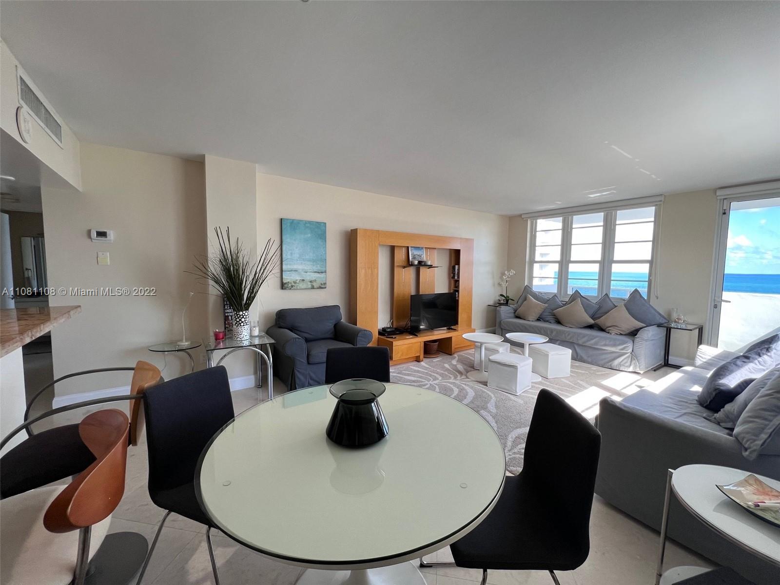 A living and dining area features a round table, grey sofas, and ocean views — 100 Lincoln Rd # 1121, Miami Beach FL 33139, MIAMI BEACH, FL