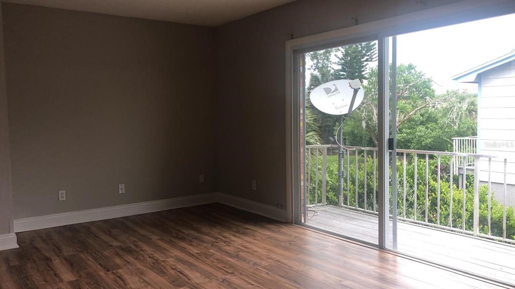 An empty room with wood-look flooring and a sliding glass door leading to a balcony — 3035 GEORGE MASON AVENUE UNIT D20, WINTER PARK, FL
