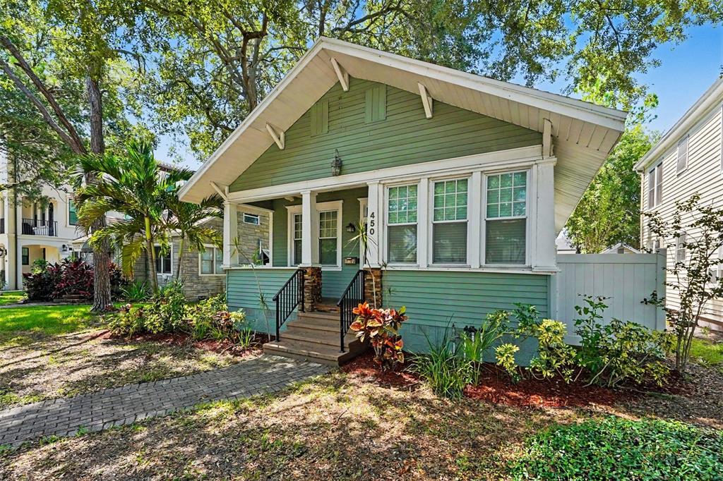 A green bungalow with a front porch, white trim, and a brick walkway — 450 13TH AVENUE N, ST PETERSBURG, FL