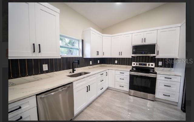 A modern kitchen features white cabinets, stainless steel appliances, and a dark patterned tile backsplash — 2902 ROBINSON ROAD, PLANT CITY, FL