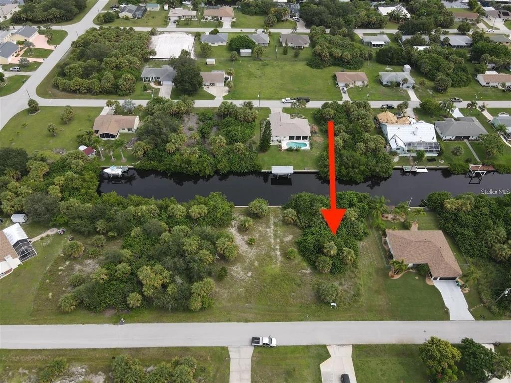 An aerial view shows a vacant, wooded residential lot situated along a canal — 18694 ARAPAHOE CIRCLE, PORT CHARLOTTE, FL